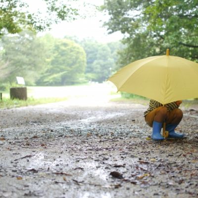 雨の道でしゃがむ子ども